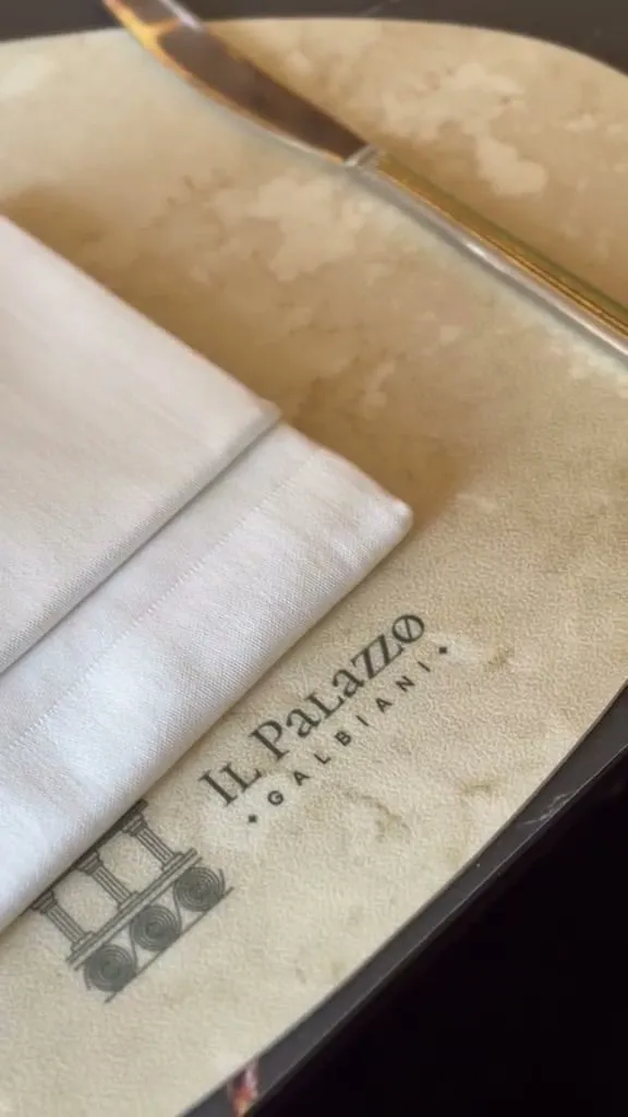 Znak Il Palazzo Galbiani utisnut na podmetaču, uz presavijeni ubrus
